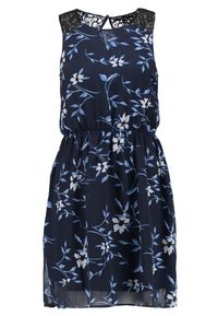 Marinblå blommig klänning med detalj i spets på axeln, ärmlös design, elastisk midja och vita blommönster på ett svävande tyg.