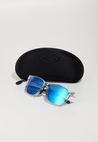Sonnenbrille mit einem klaren Acrylrahmen und blauen, verspiegelt Linsen, begleitet von einem schwarzen Hartschalenetui mit Reißverschluss.