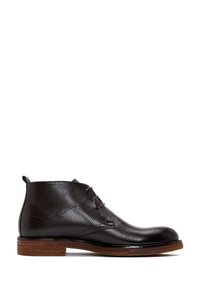 Botte mi-mollet en cuir noir avec trois œillets, semelle en bois empilée marron, et une languette au talon, présentée de profil sur un fond blanc.