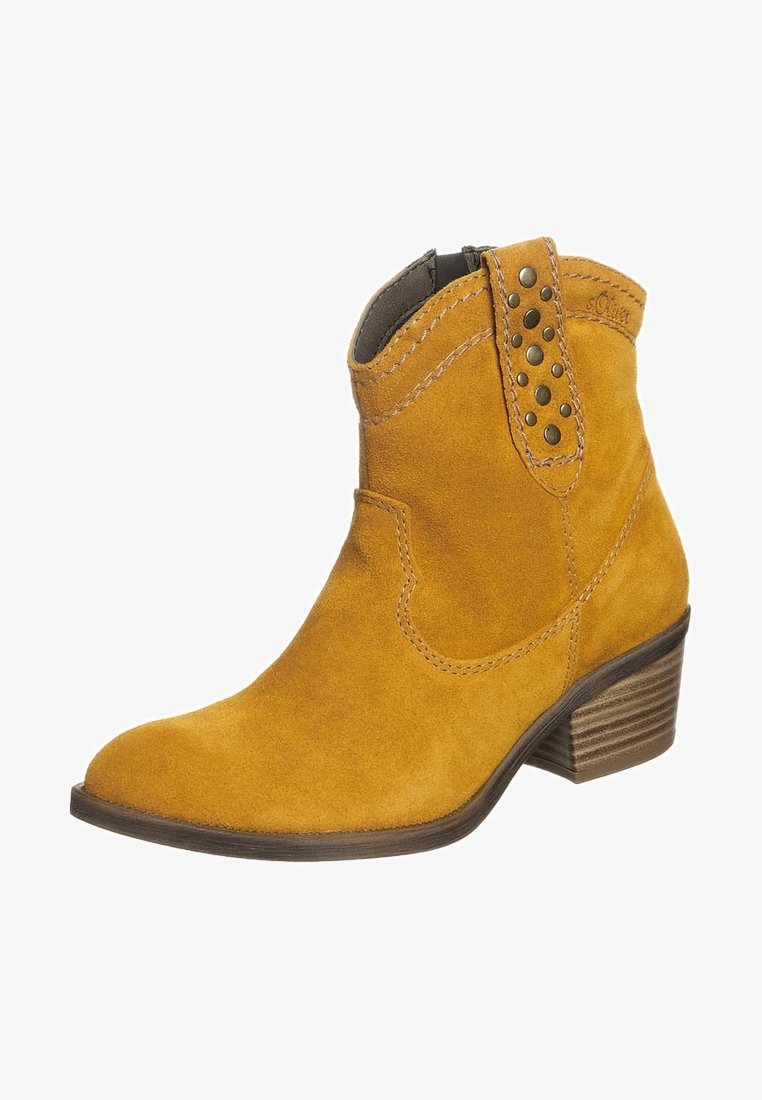 Bottine en daim jaune avec talon empilé en bois, clous métalliques décoratifs sur la languette de tirage et coutures décoratives sur la tige.