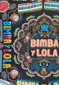 Mnohofarebná látka s odvážnou typografiou, kvetinovými vzormi a zložitými vzormi na čiernom pozadí. Obsahuje text "BIMBA y LOLA."