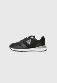 Black sneaker with mesh and leather material, featuring a triangular logo, contrasting white sole, and lace closure with reinforced eyelets.