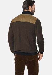 Brown textured jacket with a contrasting tan yoke and black collar, featuring ribbed cuffs and waistband. Brown corduroy pants visible.