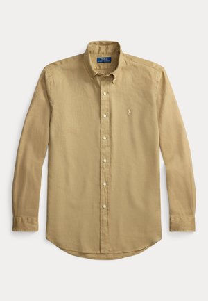 Chemise à manches longues avec boutons en kaki. Fabriquée en tissu texturé avec un ourlet droit, elle présente un petit logo brodé sur la poitrine.