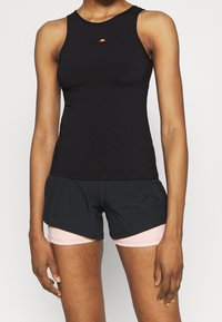 Černý bezrukávový sportovní top s kulatým výstřihem, se malým červeným a žlutým logem. V kombinaci s černými sportovními šortkami s růžovými pruhy.
