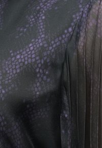 Schwarzer Stoff mit einem lila Schlangenhautmuster, das auf einer Seite plissierte Details aufweist. Glatte Textur mit einem dezenten Glanz.