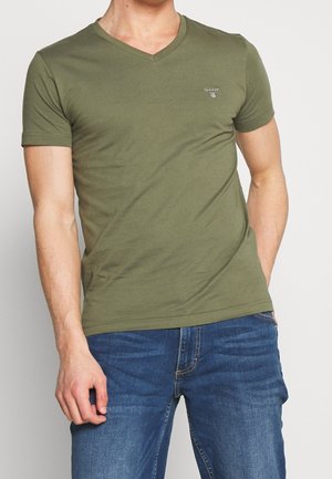 Oliven grøn kortærmet V-hals T-shirt lavet af bomuld med en tætsiddende pasform; lille logodetalje på brystet; kombineret med blå jeans.