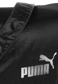Borsa da viaggio nera con superficie testurizzata, caratterizzata da un grande logo Puma argentato e una tracolla elegante e resistente.