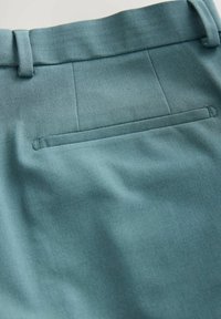Krojene hlače od mekog teal materijala, s čistim završetkom, ravnim prednjim dijelom i diskretnim stražnjim džepom ušivenim u dizajn.