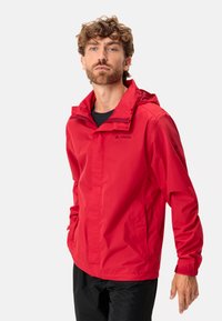 Giacca impermeabile rossa con cappuccio, realizzata in materiale leggero. Presenta due tasche laterali e un logo nero sul petto e sulla manica.