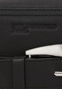 Černý kožený pásek s texturovaným povrchem a embosovaným logem "KARL LAGERFELD JEANS". Stříbrná kovová spona dodává elegantní akcent.