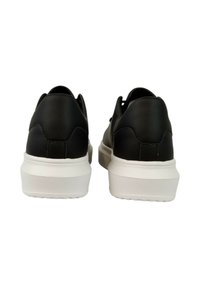 Sneaker nere con finitura in pelle liscia, suola bianca spessa e forma arrotondata; presentano cuciture minime e un design a taglio basso.