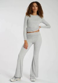 Graues Langarmoberteil mit einem Twist-Detail, kombiniert mit passenden grauen Schlaghosen. Weicher, strukturierter Stoff; lässiger sportlicher Stil.