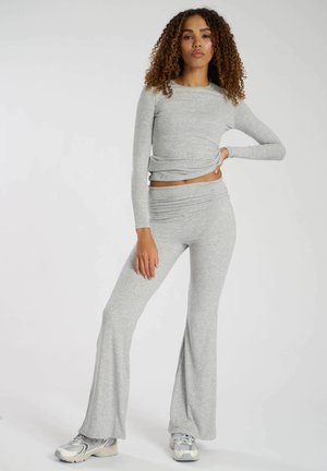 Gray long-sleeve top with a twist detail, paired with matching gray flared pants. Soft, textured fabric; casual athletic style.