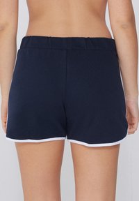 Shorts sportivi blu navy con tessuto liscio, vita elastica e bordo bianco in contrasto lungo l'orlo e le cuciture laterali.