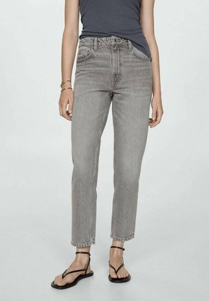 Helle graue High-Waist-Jeans mit geradem Bein, die eine Färbung, ein Fünf-Taschen-Design und einen rohen Saum aufweisen. Getragen mit schwarzen Riemchensandalen.