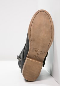 Černé nubukové kotníkové boty s hladkým, zaobleným špičkou. Plochá, texturovaná podrážka s béžovou gumou a potiskem loga na patě. Dvojité páskové detaily.