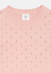 Suéter de punto rosa claro con un escote en forma de concha, que presenta un patrón texturizado de pequeñas formas de diamante en toda su superficie. Etiqueta de la marca visible.