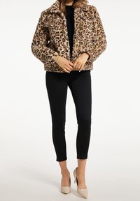 Leoprint-Faux-Fur-Jacke mit Kragen, Vorderknöpfen und zwei Brusttaschen. Kombiniert mit schwarzen skinny Hosen und beigen Absatzschuhen.