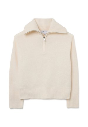 Sweat �à zip beige clair avec un col et des poignets côtelés. Texture douce, design cropped et surface lisse subtile.