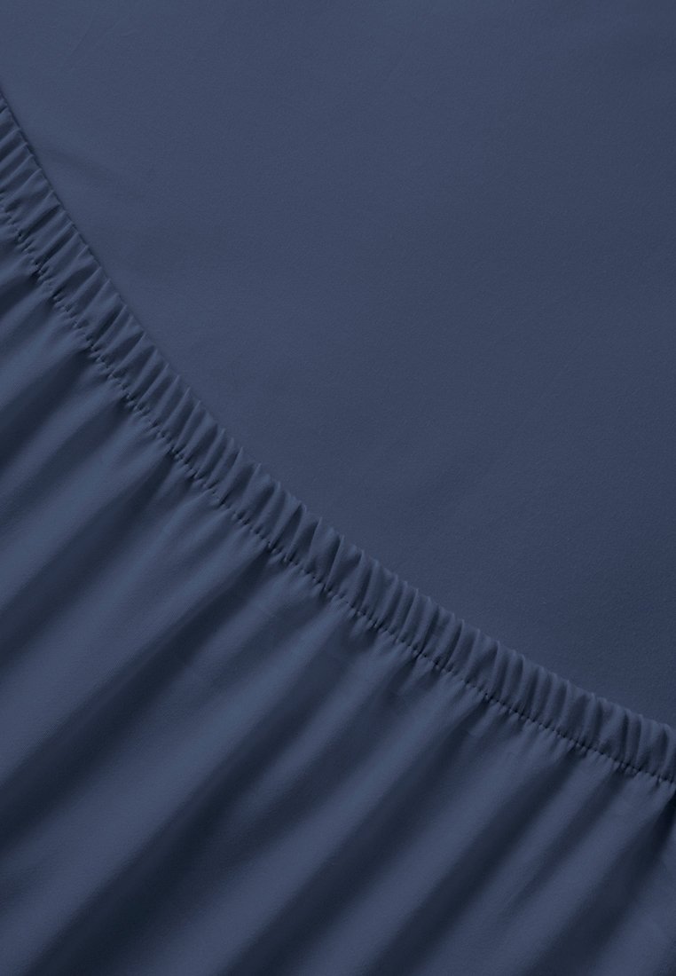Tessuto blu navy con una texture liscia presenta elastico arricciato lungo il bordo, creando un aspetto a strati e arricciato su un lato.