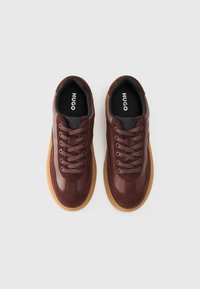 Brown leather and suede sneakers with rounded toe, lace-up design, and rubber outsole. Insole features "HUGO" branding.