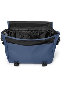 Blaue Stoff-Umhängetasche mit schwarzem Innenraum, ausgestattet mit Reißverschlüssen, einer Fronttasche und verstellbaren Riemen. Mattes Finish, robuste Konstruktion.