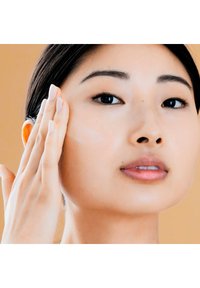 Een persoon die een romige huidverzorgingsproduct op hun wang aanbrengt. De huid is glad en helder, met natuurlijke tinten en minimale make-up.