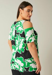 Top a fantasia floreale con grandi fiori verdi e bianchi su uno sfondo nero, con maniche corte e design off-shoulder.