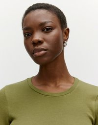 Olivegrünes, geripptes Oberteil mit Rundhalsausschnitt, taillierter Form und kurzen Ärmeln. Das Model hat kurze Haare und trägt silberne Creolen.