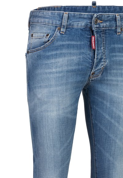 Jean en denim bleu avec poches avant, fermeture par boutons, passants de ceinture et une étiquette de marque en tissu rouge visible sur le côté droit.