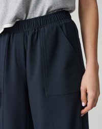 Pantalons larges bleu marine avec une taille élastique, dotés de poches latérales et de coutures subtiles pour ajouter de la texture.