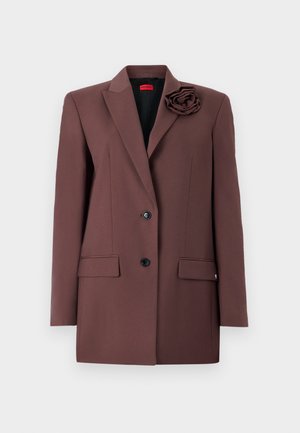 Brown blazer with a structured design, single button closure, front pockets, and a fabric flower accent on the collar. Smooth texture.