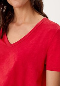 Rød V-hals t-shirt med korte ærmer, lavet af letvægtsstof med en let struktur og en afslappet pasform.