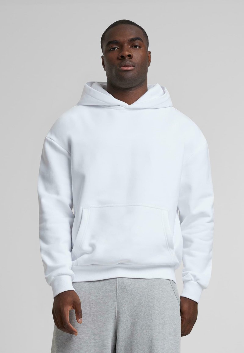 White hoodie featuring a kangaroo pocket, drawstring hood, and ribbed cuffs, paired with gray sweatpants. Smooth texture, casual design.