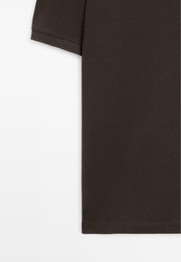 Donkerbruin poloshirt met korte mouwen, gemaakt van textuurstof, met zichtbare naad aan de mouw en zoom onderaan, op een witte achtergrond.