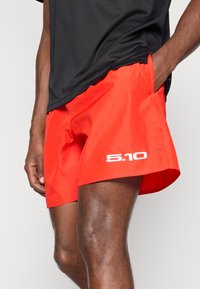 Κόκκινες βερμούδες από ελαφρύ ύφασμα, με ελαστική μέση και πλαϊνές τσέπες. Το λογότυπο "5.10" εμφανίζεται έντονα μπροστά.