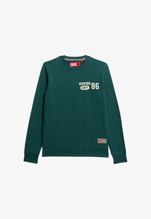 Ciemnozielony sweatshirt z okrągłym dekoltem, z białym napisem "SUPER DRY 86", ściągaczami na rękawach i u dołu. Zawiera naszywkę z logo na dolnej części.