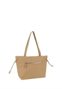 Beige tote bag, lavet af glat materiale, har en guld lynlåslomme foran, justerbare sideløft og to robuste skulderstænger.