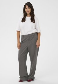 Pantalons gris clair taille haute avec une coupe droite, dotés de poches latérales et d'une texture de tissu lisse. Associés à un t-shirt blanc.