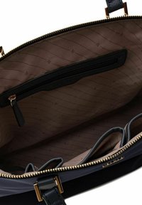 Interno di una borsa in pelle nera con rivestimento in tessuto marrone con un sottile motivo a righe, tasca con zip e scomparti per l'organizzazione.