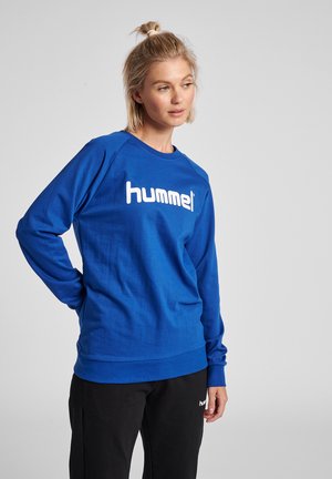 Blauwe katoenen sweatshirt met lange mouwen, ronde halslijn en wit "hummel" logo op de borst. Glad textuur, normale pasvorm en ribgebreide zoom.