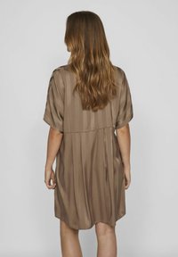 Abito a righe marroni in tessuto satin, con maniche corte e vestibilità ampia. Il design presenta una leggera lucentezza e un orlo fino al ginocchio.