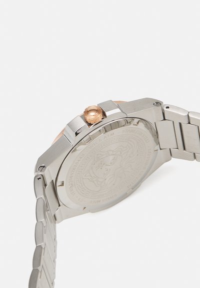 Nerūdijančio plieno laikrodis su rožinės aukso karūna, kvadratu korpusu, metaliniu apyrankė ir graviruotu raštu ant nugarėlės.