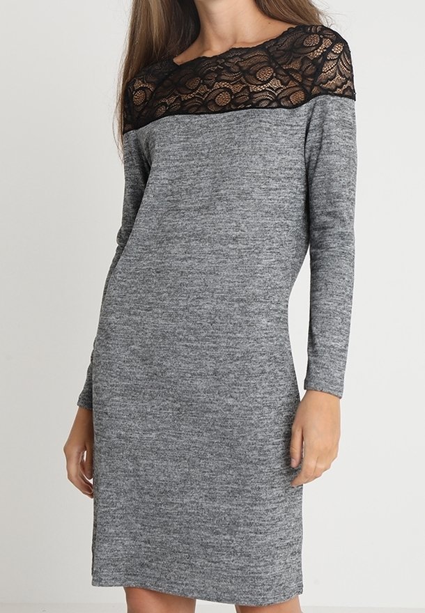 Robe grise à manches longues avec un yoke en dentelle noire, texture en tricot lisse et coupe droite. Des fentes latérales ajoutent un détail subtil.