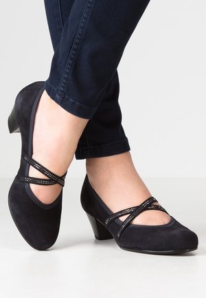 Escarpins en suède bleu marine avec une pointe arrondie, dotés de brides croisées ornées de petits strass et d'un petit talon carré.