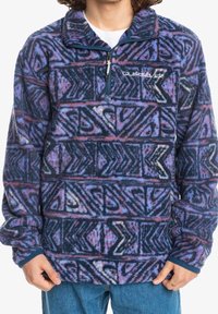 Pullover in pile blu navy, viola e rosa con un motivo geometrico astratto; presenta un collo con cerniera e polsini elastici.