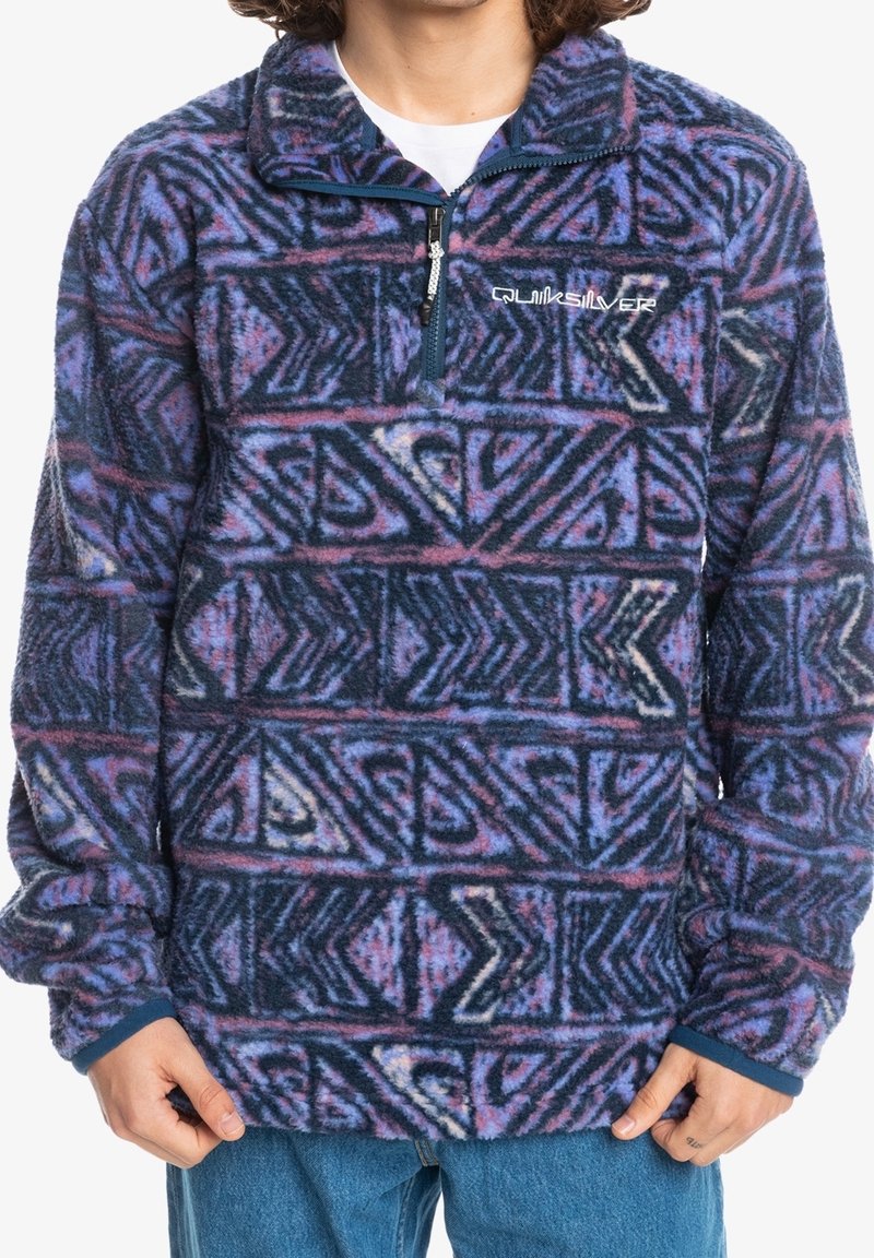 Pullover in pile blu navy, viola e rosa con un motivo geometrico astratto; presenta un collo con cerniera e polsini elastici.