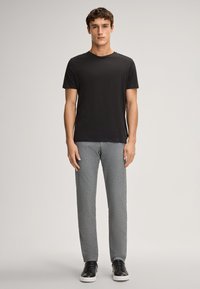 Zwarte T-shirt met korte mouwen, grijze gestreepte broek en zwarte sneakers. De outfit heeft een casual pasvorm met een ronde hals.