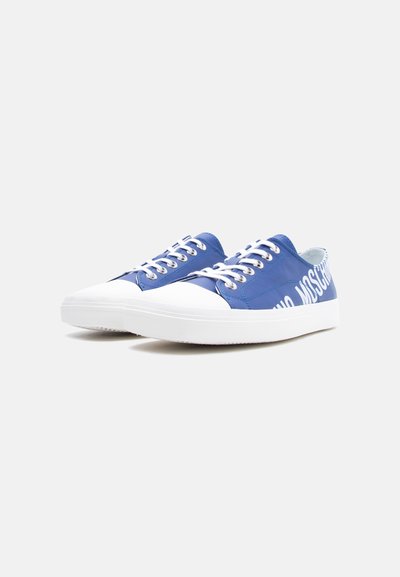 Ζευγάρι μπλε αθλητικά παπούτσια χαμηλής κοπής με λευκές ελαστικές σόλες, λευκά κορδόνια και έντονο λευκό κείμενο λογότυπου στο πλάι.